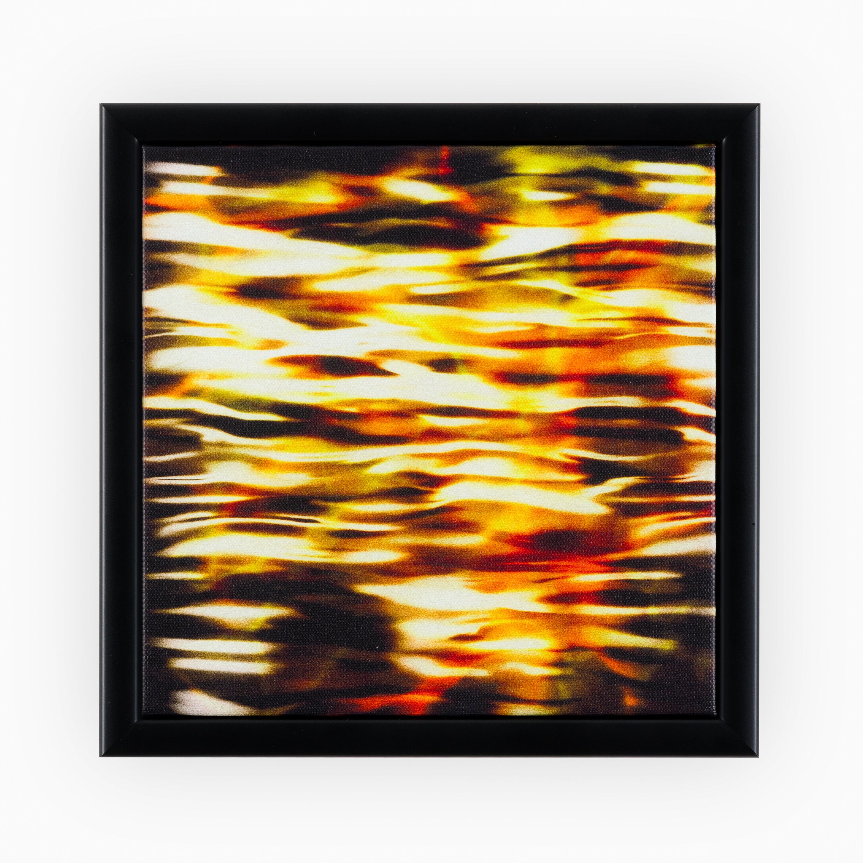 Abstract canvas art capturing the reflection of a city's lights on water with golden yellow and orange hues intermingling, symbolising the bustling night-life, bordered by a classic black frame.